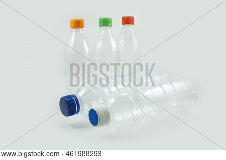Close-up Of Used Plastic Bottles For Recycling With Colorful Bottle Caps Isolated On A White Backgro