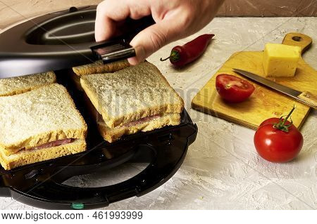 A Man Making Sandwiches In A Sandwich Maker Closes The Lid Of A Sandwich Maker