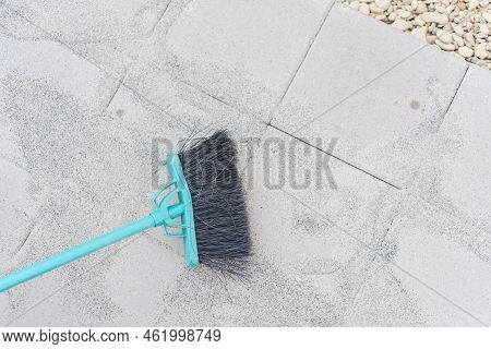 Plastic Broom To Fill Polymeric Paver Sand On Top Of Gray Concrete Patio Stone Paver Brick Walkway