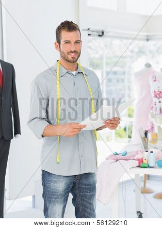 Portrait of a young male fashion designer holding sketch in the studio