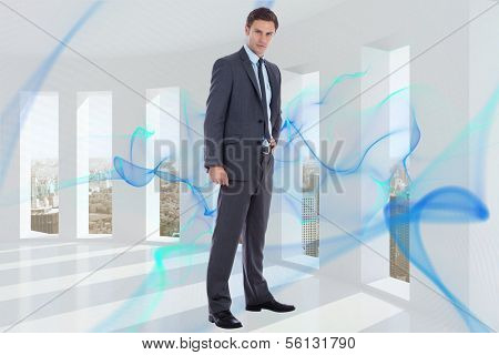 Serious businessman with hand on hip against blue abstract design in room