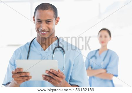 Portrait of a happy handsome male doctor holding digital tablet in the hospital