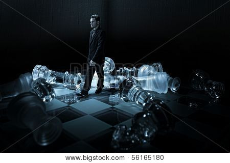 Businessman on a chessboard walk from the capsized dummies