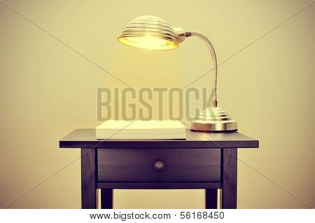 picture of an old gooseneck lamp and a stack of blank paper sheets on a bureau, with a retro effect