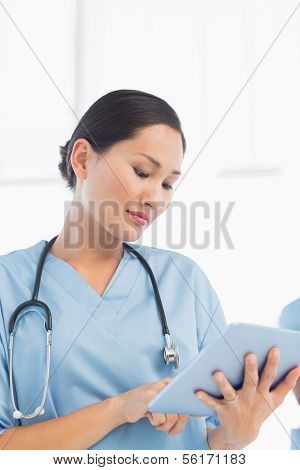 Portrait of a beautiful female surgeon using digital tablet in the hospital