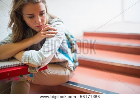 Sad lonely student sitting on stairs in college