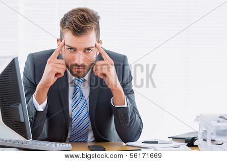 Portrait of a young elegant businessman with headache sitting at office desk