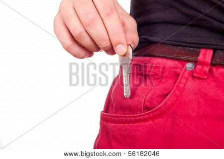 рука кладет старинный ключ в карман джинсов