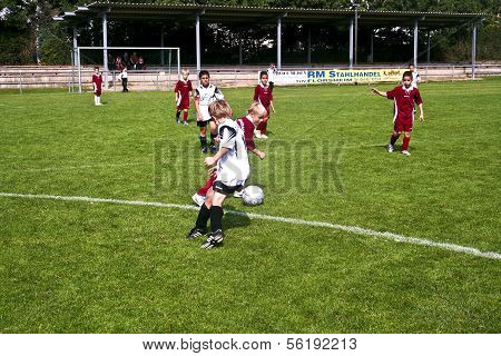 Children Playing Soccer In Summer In An Outdoor Grass Arena