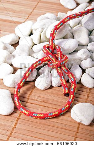 A fine knotted bowline next to a pile of stones