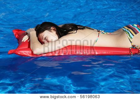A very attractive young woman taking a sunbath on her red airbed