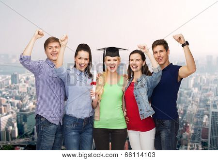 education and people concept - group of standing smiling students with diploma and corner-cap
