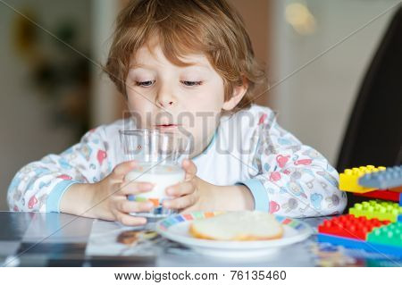 Little Kid Boy Drinking Milk And Playing With Construction Blocks
