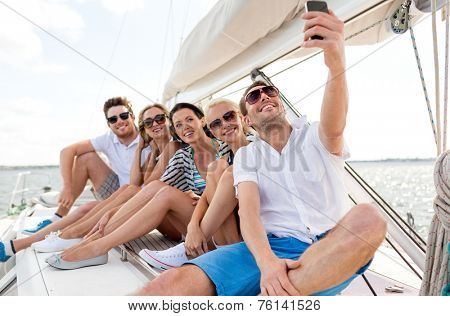 vacation, travel, sea, friendship and people concept - smiling friends sitting on yacht deck and making selfie