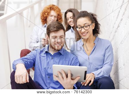 business, technology and startup concept - smiling creative team with tablet pc computer sitting on staircase