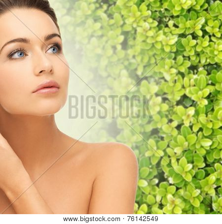 beauty, people and ecology concept - beautiful young woman touching her face skin over green background