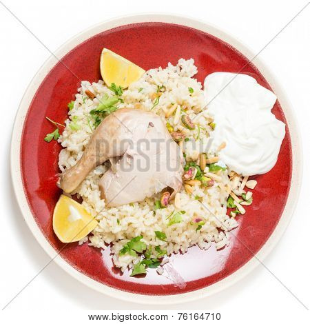 Chicken pilaf, or riz bi djaaj, traditional Arab and Mediterranean boiled chicken and rice dish, served with roasted nuts and lemon wedges.