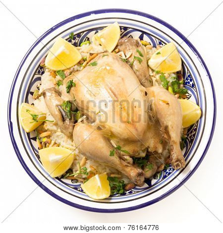 Chicken pilaf, or riz bi djaaj, traditional Arab and Mediterranean boiled chicken and rice dish, served with roasted nuts and lemon wedges.