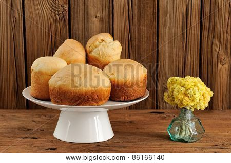 Paska, East European Easter Sweet Breads On White Pedestal With Yellow Flowers On Wooden Background