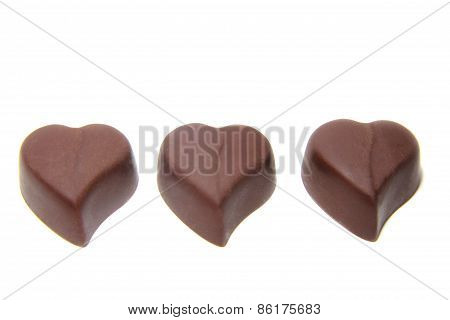 three chocolate candy in the shape of heart on white background