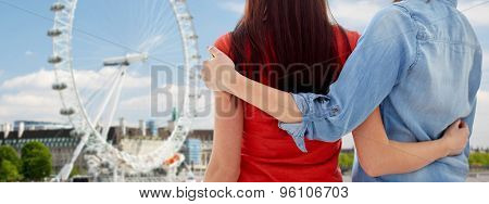 people, homosexuality, same-sex marriage, travel and gay love concept - close up of happy lesbian couple hugging over london ferry wheel background