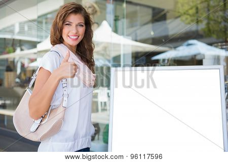 Portrait of smiling woman standing next to blank board at the shoppingmall