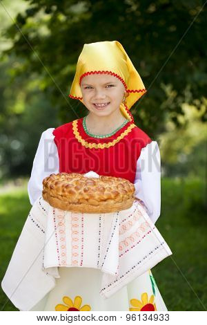 Little girl is dressed in the Russian national dress. She holds in his hands the fresh loaf. It is a custom to meet the guests.