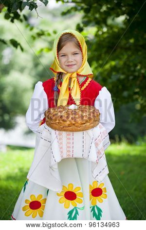 Little girl is dressed in the Russian national dress. She holds in his hands the fresh loaf. It is a custom to meet the guests.