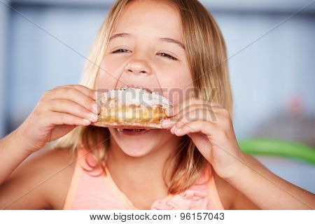 Young Girl Sitting At Table Eating Sugary Donut