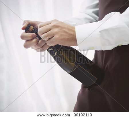 Professional Male Waiter In Uniform Opening Bottle Of Champagne