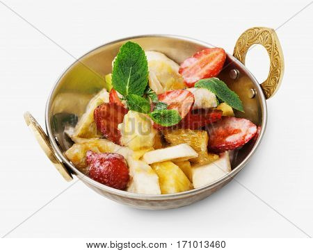 Vegan and vegetarian dish, fresh fruit and strawberry salad in copper bowl closeup isolated on white background. Indian restaurant healthy meal, dessert. Eastern local food.