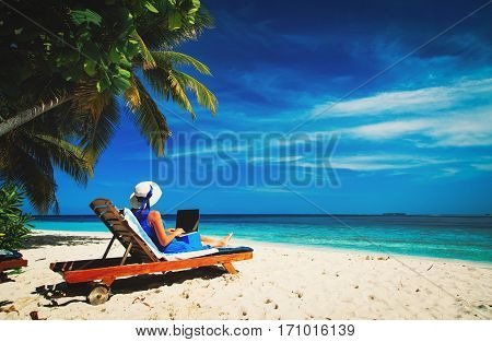 remote work concept -young woman with laptop on tropical beach