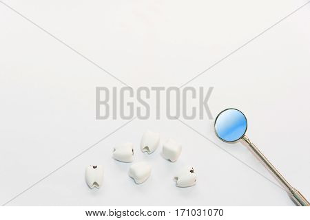 Dental care concept top view or flat lay of helathy teeth and bad teeth or caries with dentist mirror with copy space background on white