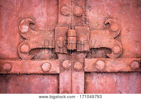 The hinge on an old metal gate red color. Close-up
