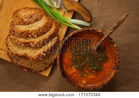 Typical eastern europe dinner contains of simple vegetable soup, rural bread and frsh onion served in traditional wooden utensils