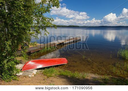 red boat on a lakes coast and sky with clouds