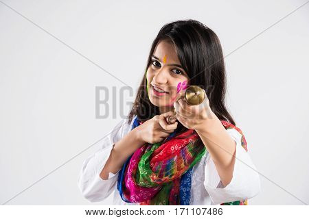 indian beautiful young female holding pichkari ready to spray colours on Holi festival, isolated over white background with copy space