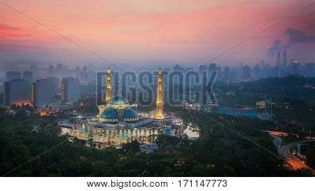 Masjid Wilayah Persekutuan in Kuala Lumpur city Malaysia. In photo show mosque and city in the mist background