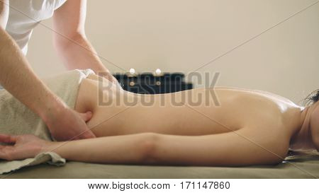 Young woman having classical massage in beauty spa, sesame oil, telephoto