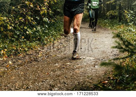 male runner runs marathon forest trail feet in mud