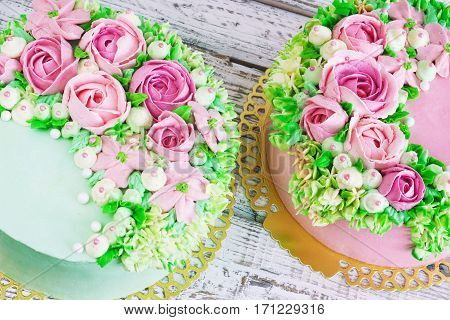 Two celebratory cake with flowers rose on a white wooden background.