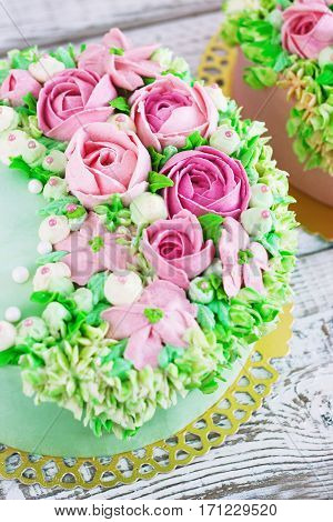 Two celebratory cake with flowers rose on a white wooden background.