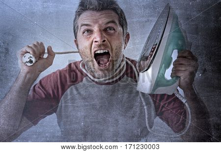 young crazy desperate and frustrated man doing housework holding iron and cable stressed and confused in unskilled and unable male for ironing isolated on even background