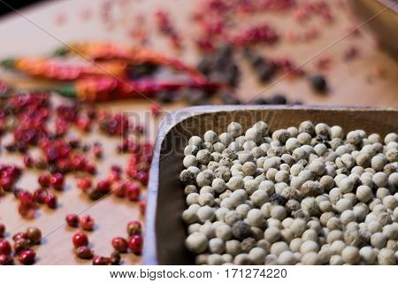 White peppercorn in wooden cup on pepper background
