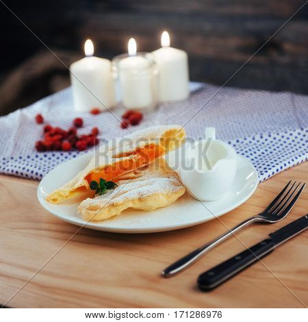 piece of freshly baked pumpkin strudel home with powdered sugar and cream and a sprig of mint