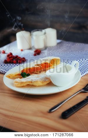 piece of freshly baked pumpkin strudel home with powdered sugar and cream and a sprig of mint