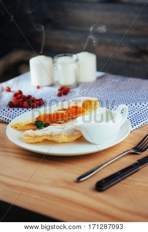 piece of freshly baked pumpkin strudel home with powdered sugar and cream and a sprig of mint