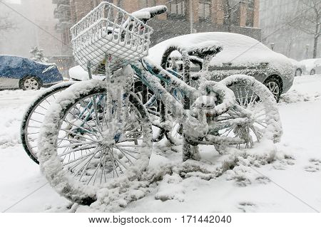 Two bicyles chained to a rack outside are covered in snow during a snowfall in Manhattan.