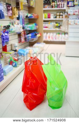 Red and green bags are on floor in supermarket Goods for Home with household chemicals