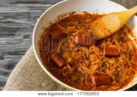 Bigus with sausages in a frying pan on a wooden background in rustic style